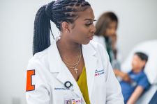Black female medical student or doctor in white doctor coat with Orange Illinois I on the sleeve