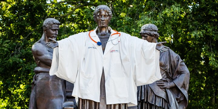 Alma mater statue in doctor's white coat with stethoscope
